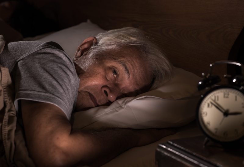 Depressed senior man lying in bed cannot sleep from insomnia